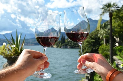 33658608 - two wineglasses in the hands against lake como, italy